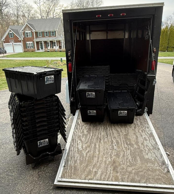 Loaded trailer in Narragansett driveway with moving crates stacked